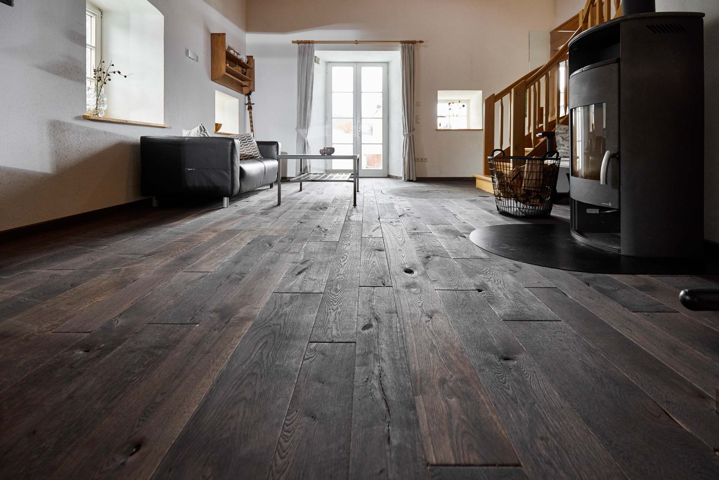 Mühlenboden im modernisierten Mühlenzimmer Wohnzimmer mit rustikalem Mühlenboden in dunkler Ausführung, moderner Einrichtung und Kaminofen in der renovierten alten Mühle.